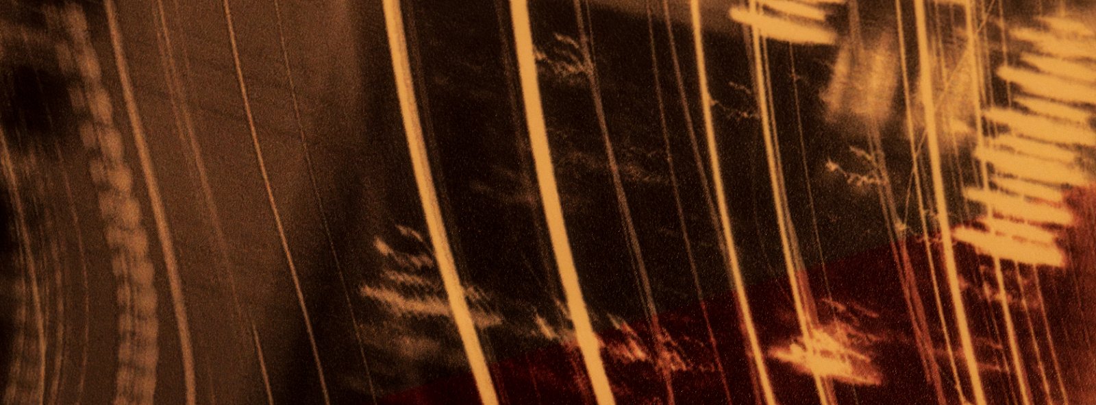 Rain streaks across a dark window with golden warm light creating a moody, atmospheric scene.